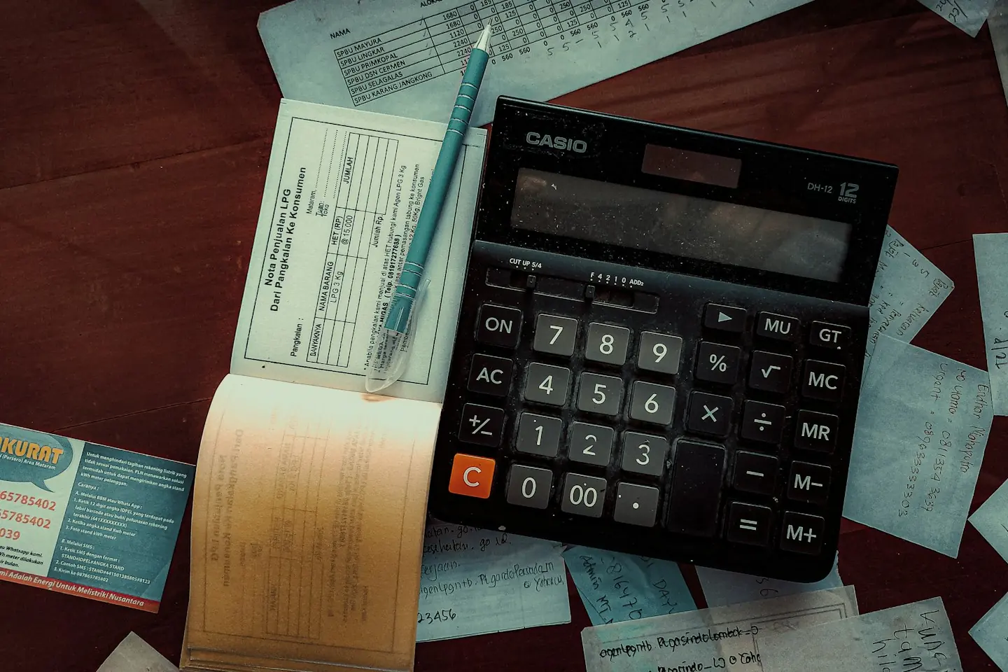 Calculatrice et justificatifs posés sur un bureau en bois